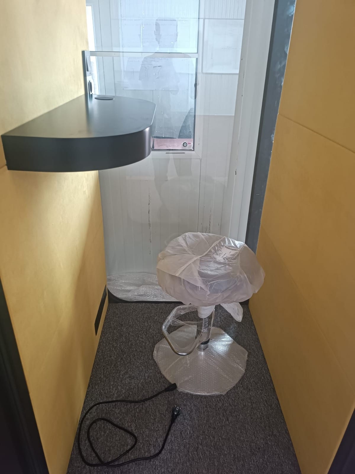 Inside a new booth: desk, socket, wrapped stool and power lead