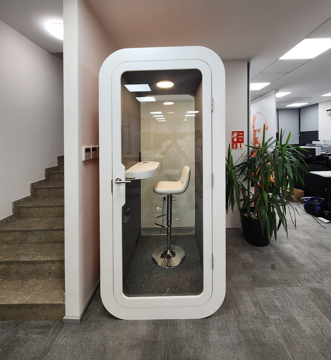 White phone booth placed beside an office staircase